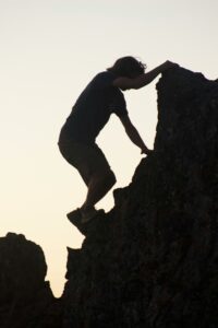 Person climbing a rock face, symbolizing perseverance and growth through hardship