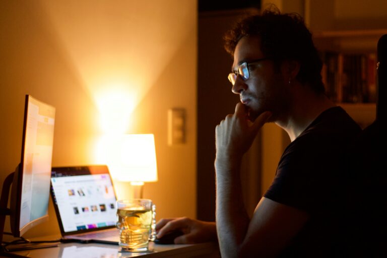 Man sitting at a desk at night, quietly writing and thinking under a warm lamp