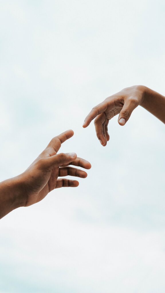 Two hands reaching toward each other without touching