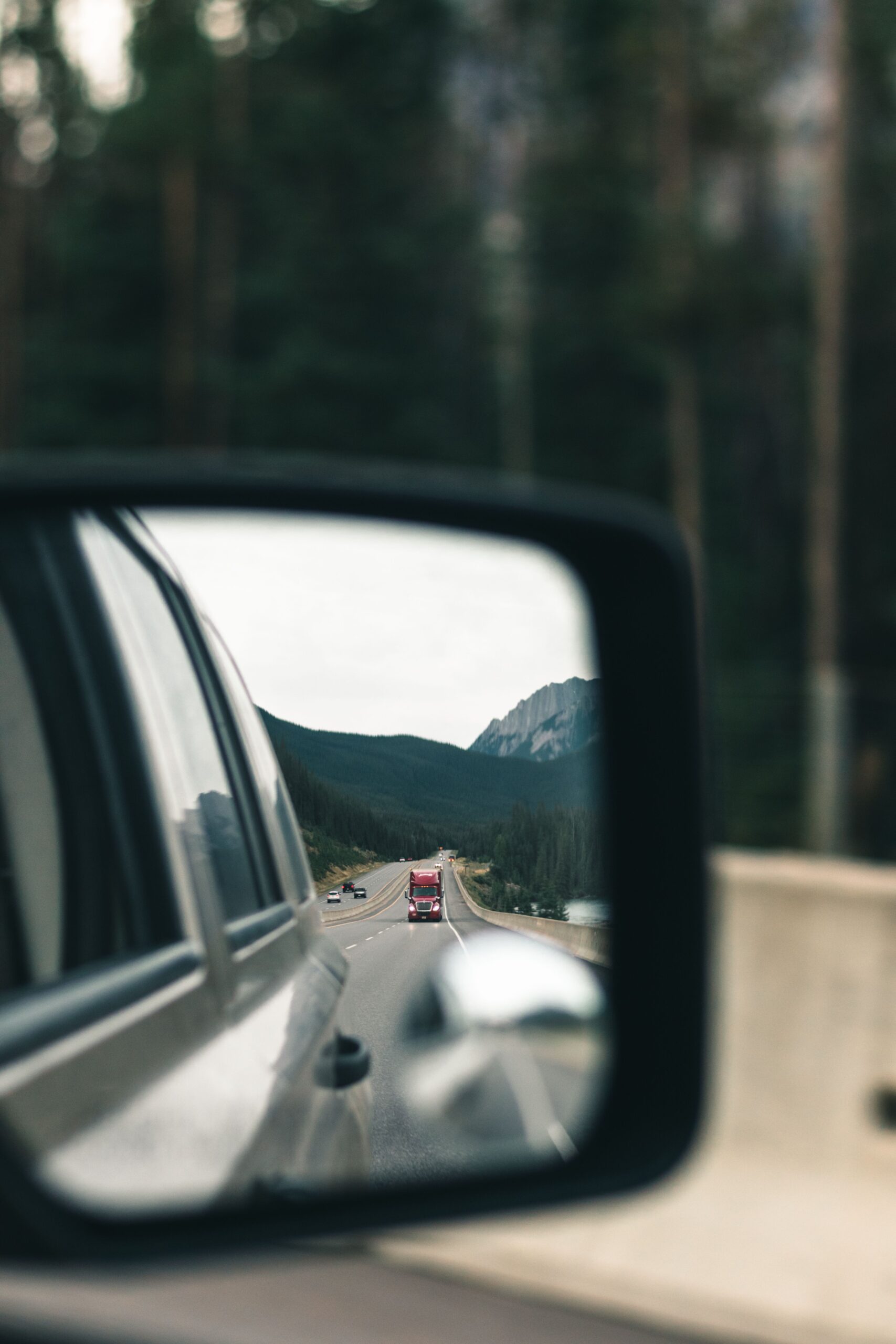 Mountain road reflected in a car side mirror while driving